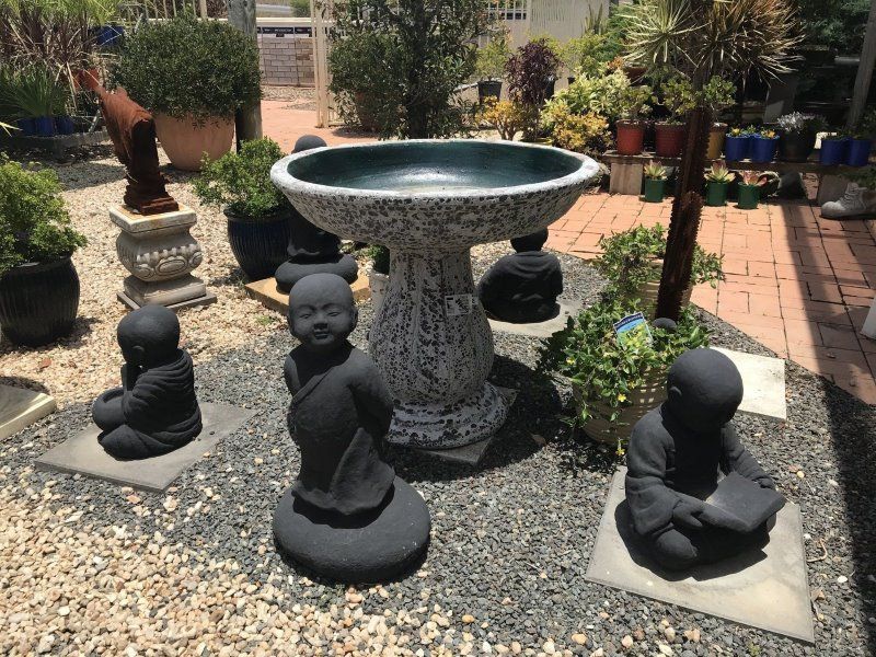 A Group of Statues Are Sitting Around a Bird Bath in a Garden — Golden City Gympie Brick & Landscape in Gympie, QLD