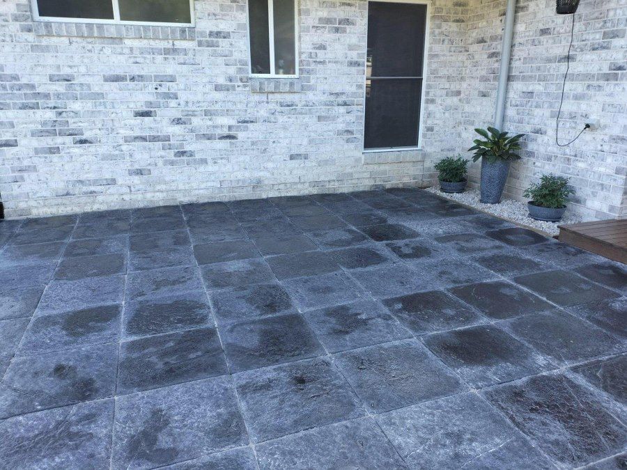 A Patio With Black Tiles in Front of a White Brick Building — Golden City Gympie Brick & Landscape in Gympie, QLD