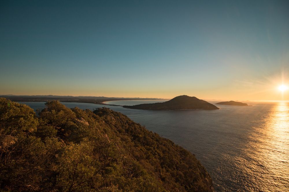 A Sunset Over a Large Body of Water With Mountains in the Background — VIP Car Care Newcastle in Port Stephens, NSW