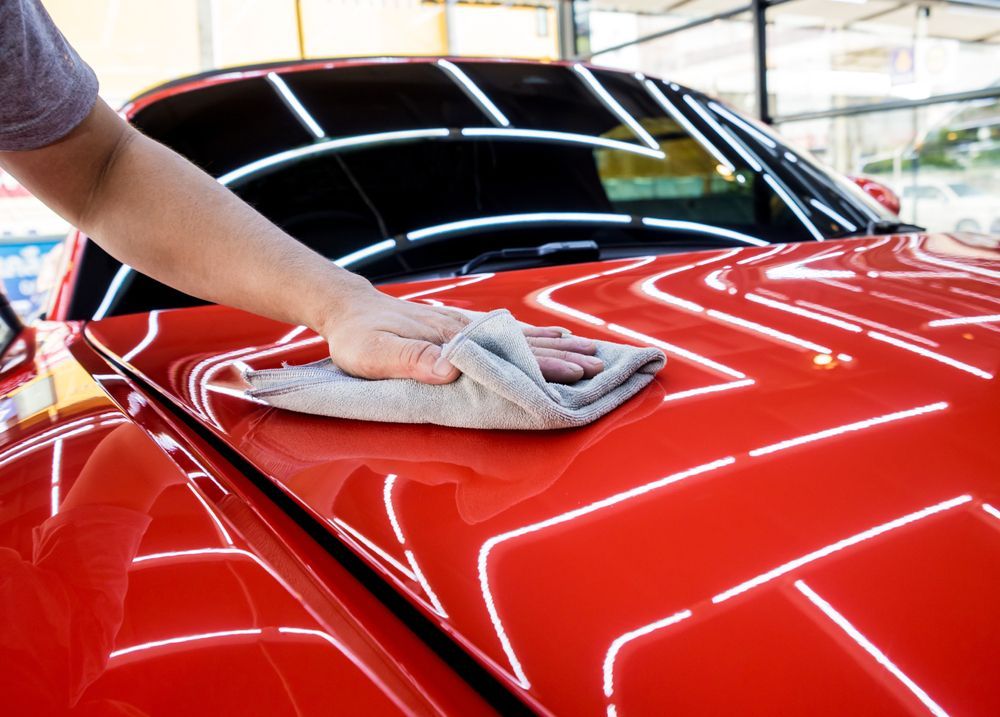 A Person is Cleaning a Red Car With a Towel — VIP Car Care Newcastle in Woy Woy, NSW