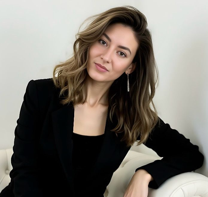 A woman in a black jacket is sitting on a white couch
