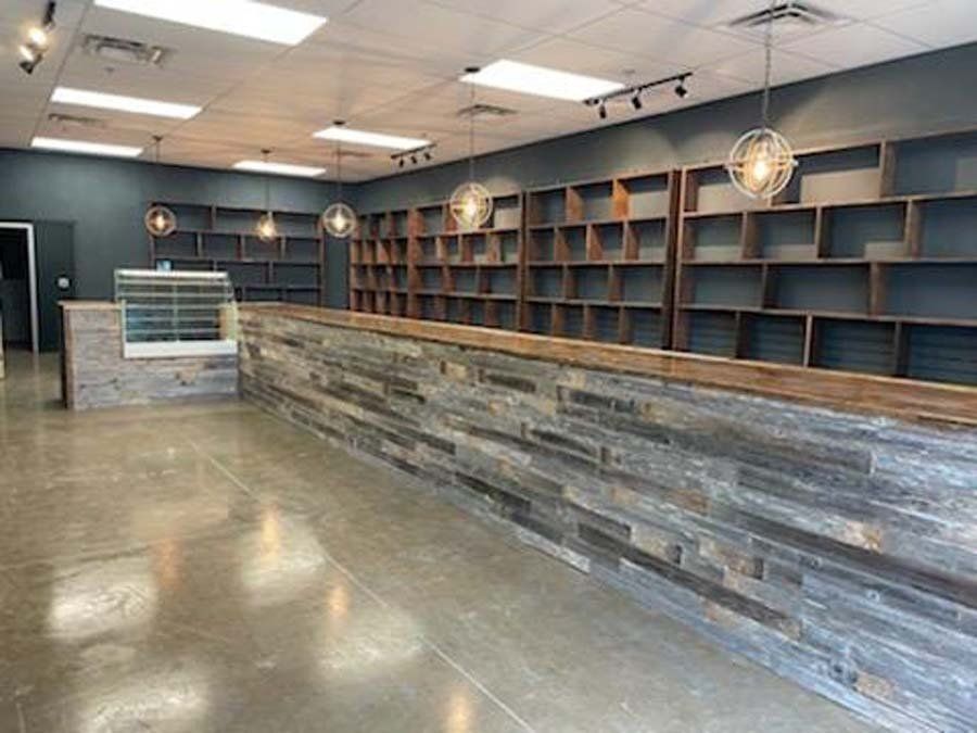 An empty store with a long wooden counter and shelves.