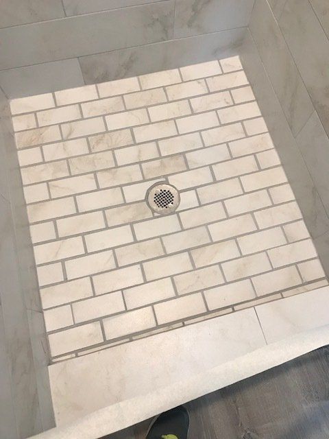 A white brick shower floor with a drain in the middle