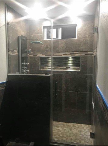 A bathroom with a walk in shower with a glass door.