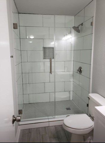 A bathroom with a toilet and a shower with a glass door.