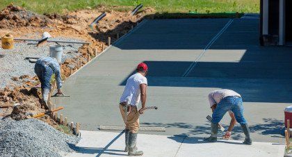 A group of construction workers are working on a concrete driveway.