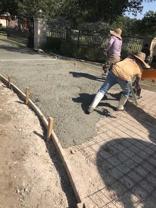 A group of construction workers are working on a driveway.