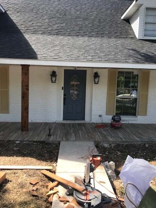 A white house with a black door and a circular saw in front of it.