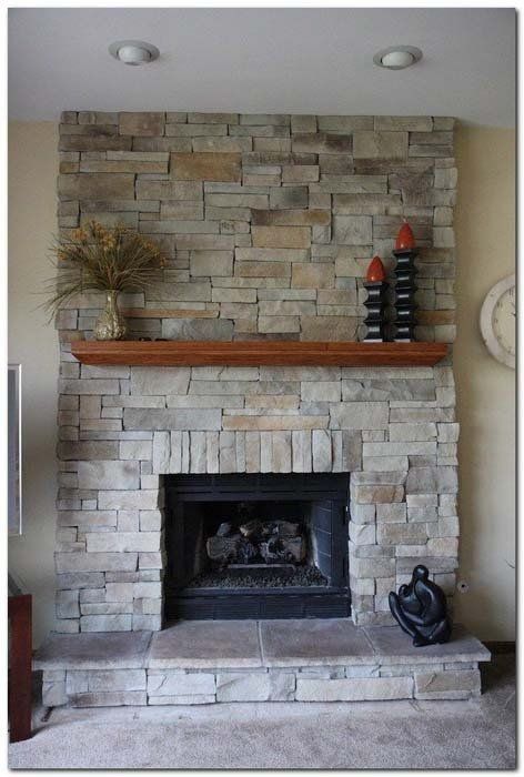 A stone fireplace with a wooden mantle in a living room