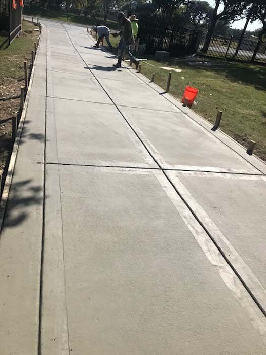 A group of people are working on a concrete sidewalk.