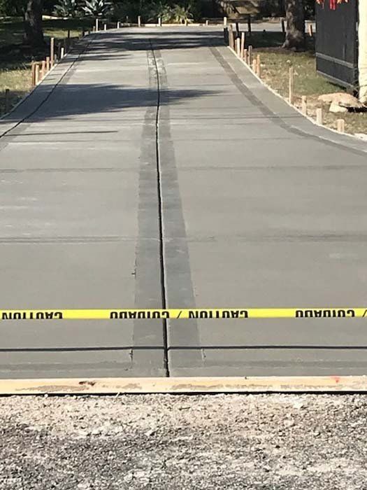 A concrete driveway is being built with yellow caution tape.