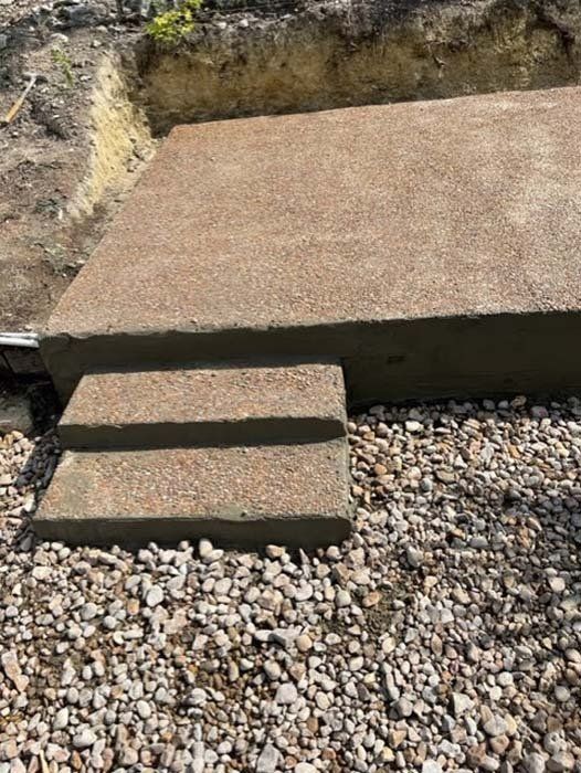 A set of concrete steps sitting on top of a pile of gravel.