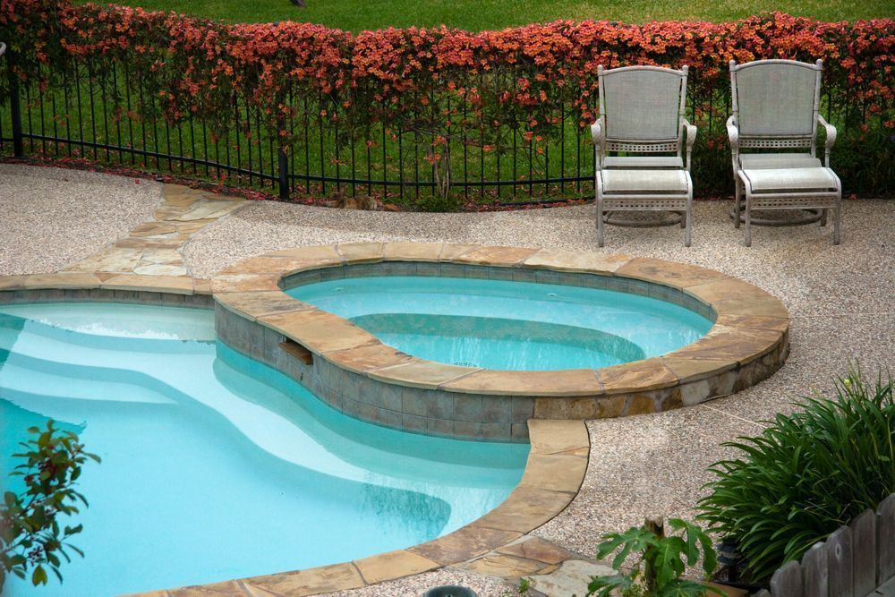 A Bright Blue Swimming Pool With an Attached Raised Hot Tub — Sun Cool Pools & Spas in Bundaberg, QLD