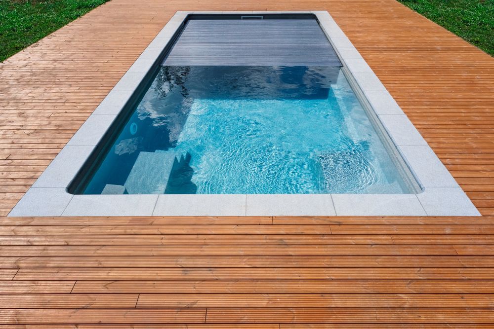 A Rectangular Swimming Pool With a Partially Closed Grey Safety Cover — Sun Cool Pools & Spas in Maryborough, QLD