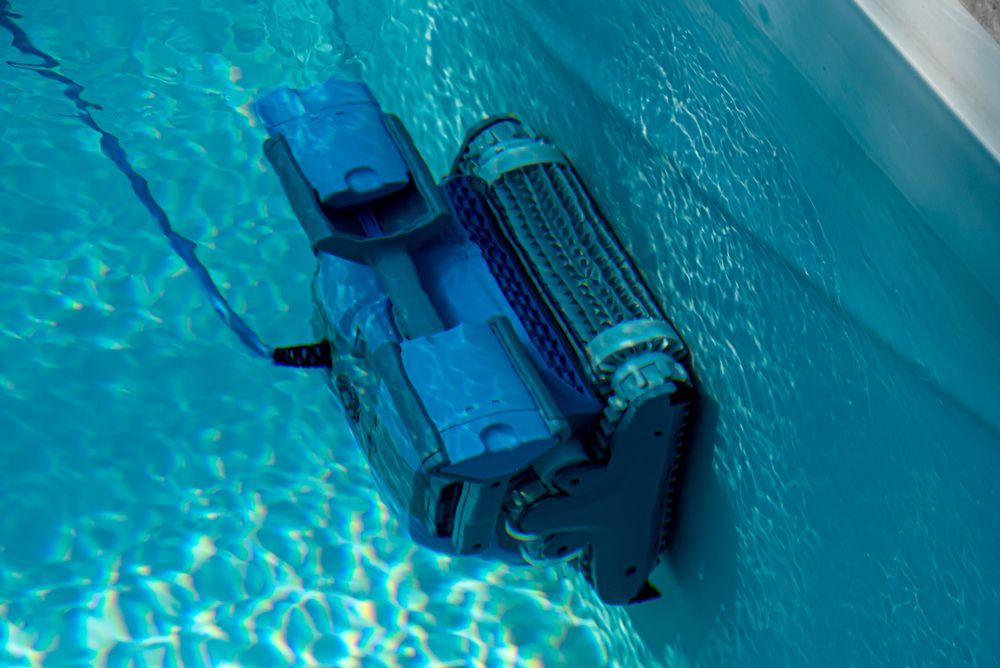 A Blue Robotic Pool Cleaner Climbing the Vertical Wall of a Pool Underwater — Sun Cool Pools & Spas in Maryborough, QLD