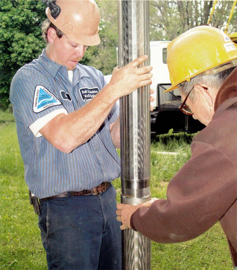 Two men working on water well drilling