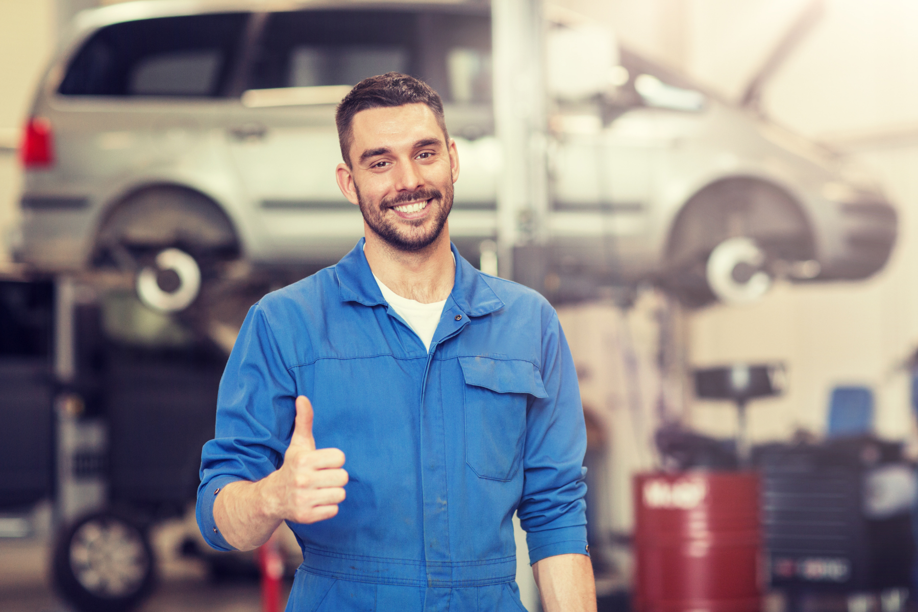 Oficina mecânica com carros em elevadores e mecânicos trabalhando. A marca Bridgestone está visível.