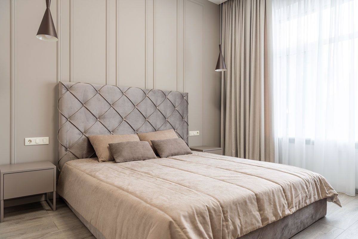 a bedroom with a bed, nightstands , curtains and a window.