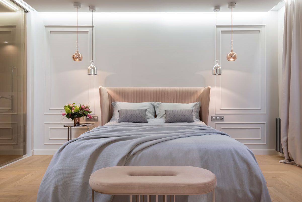 a bedroom with a bed , bench and lamps .