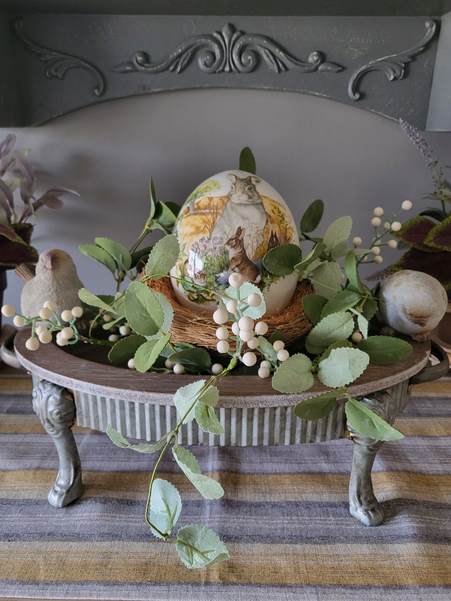 a egg is sitting on top of a table with flowers and leaves. Interior designing ideas using risers.