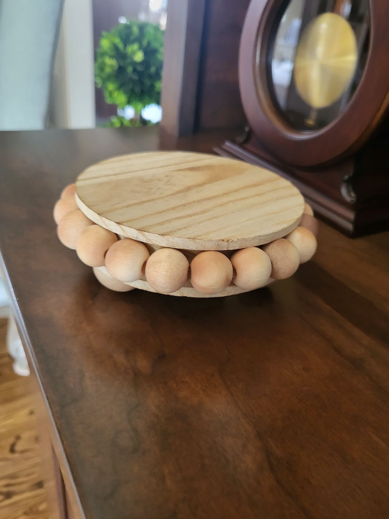 a wooden tray with beads on it is sitting on a wooden table next to a clock .