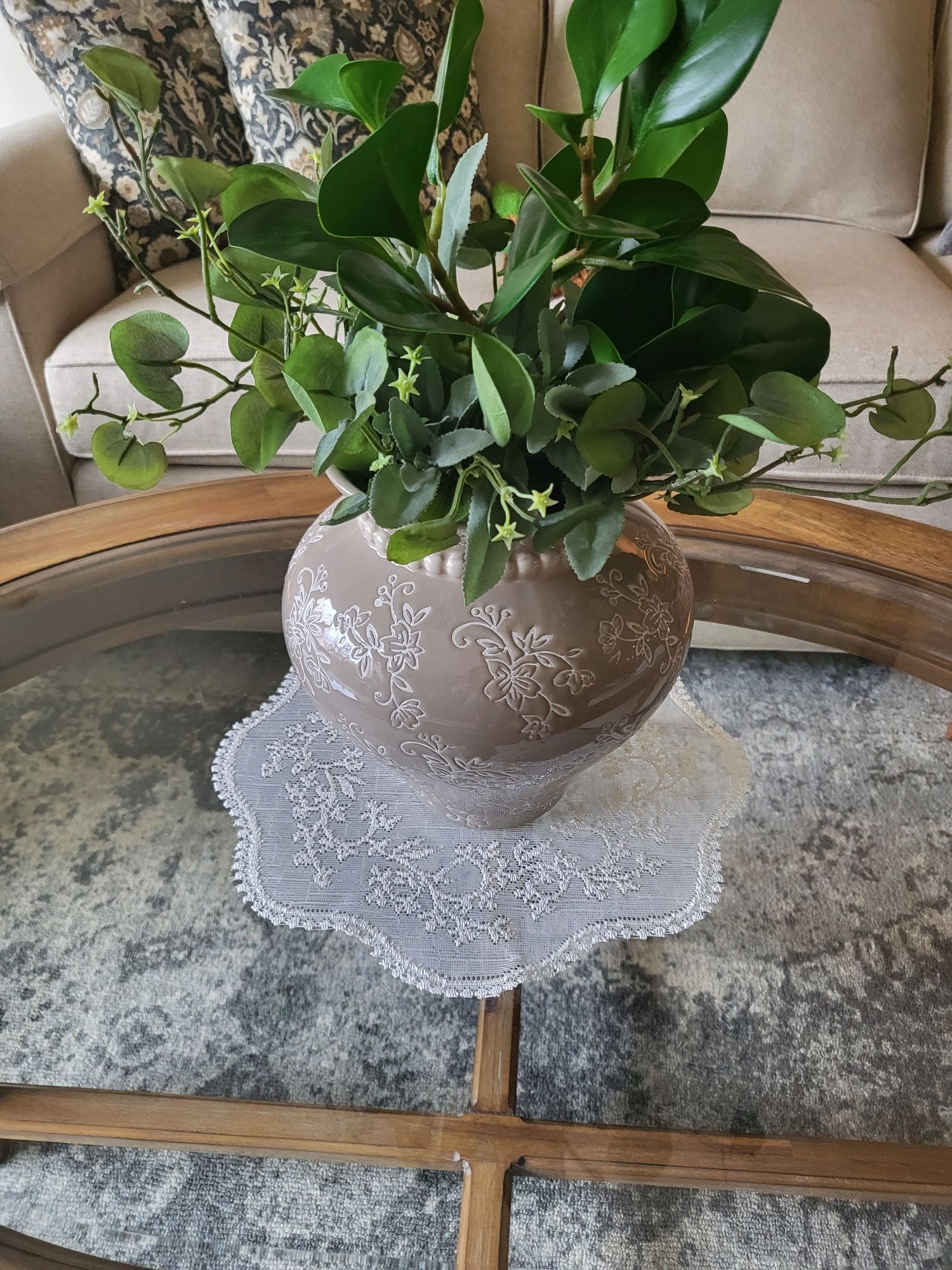 a vase with a plant in it is sitting on a glass coffee table .