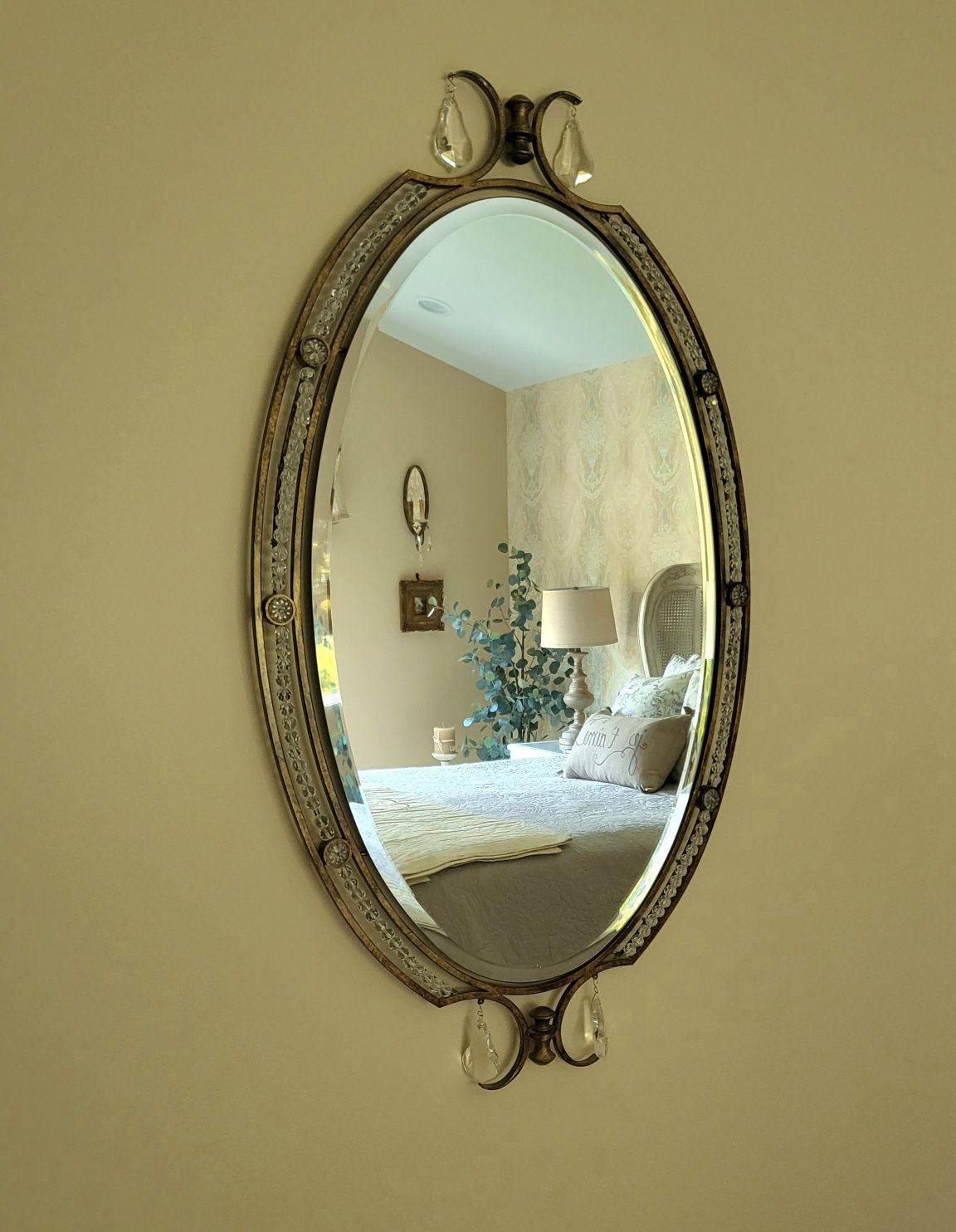 a bedroom is reflected in an oval mirror on a wall
