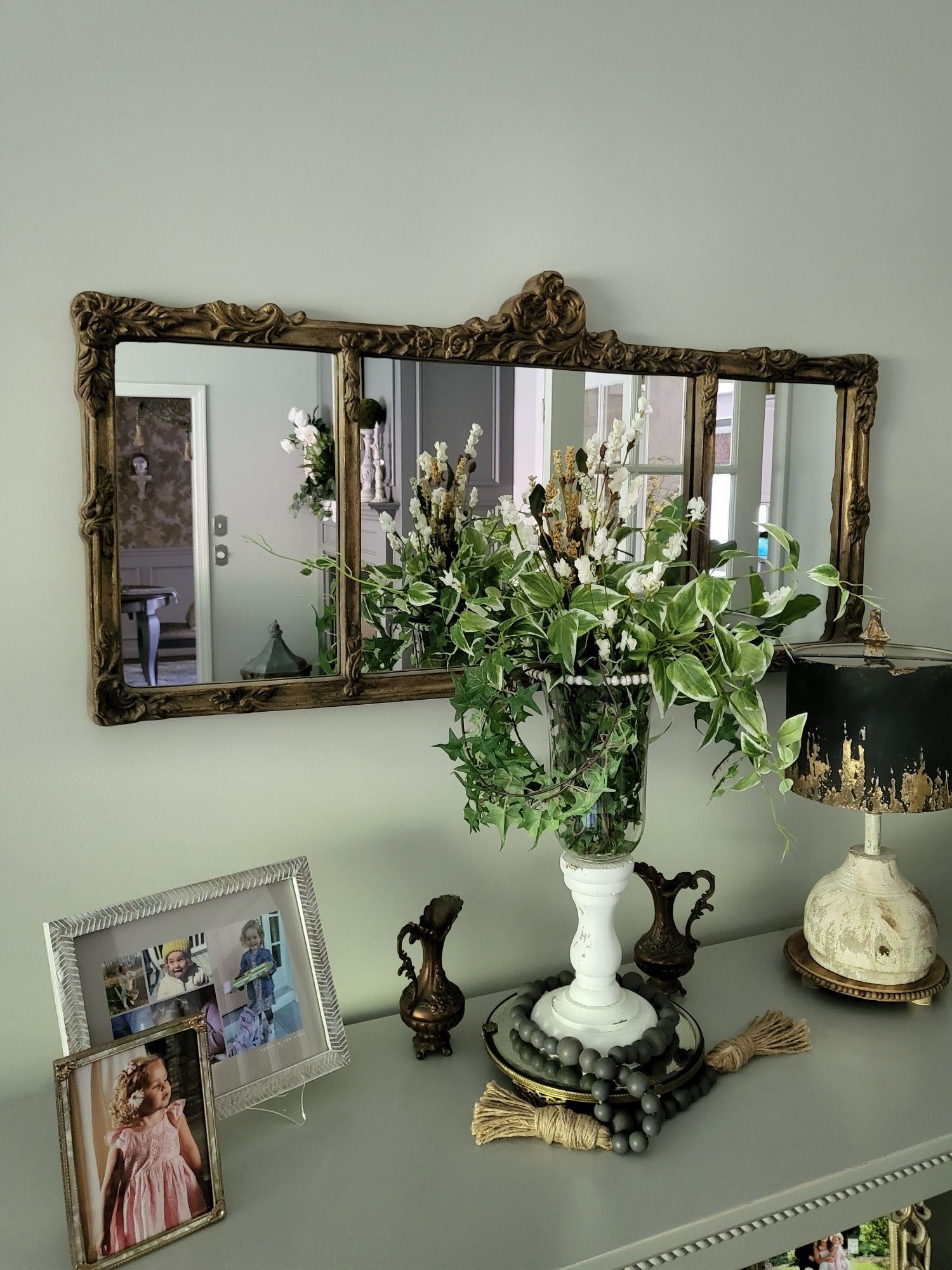 a large mirror is hanging on a wall above a table with a vase of flowers .