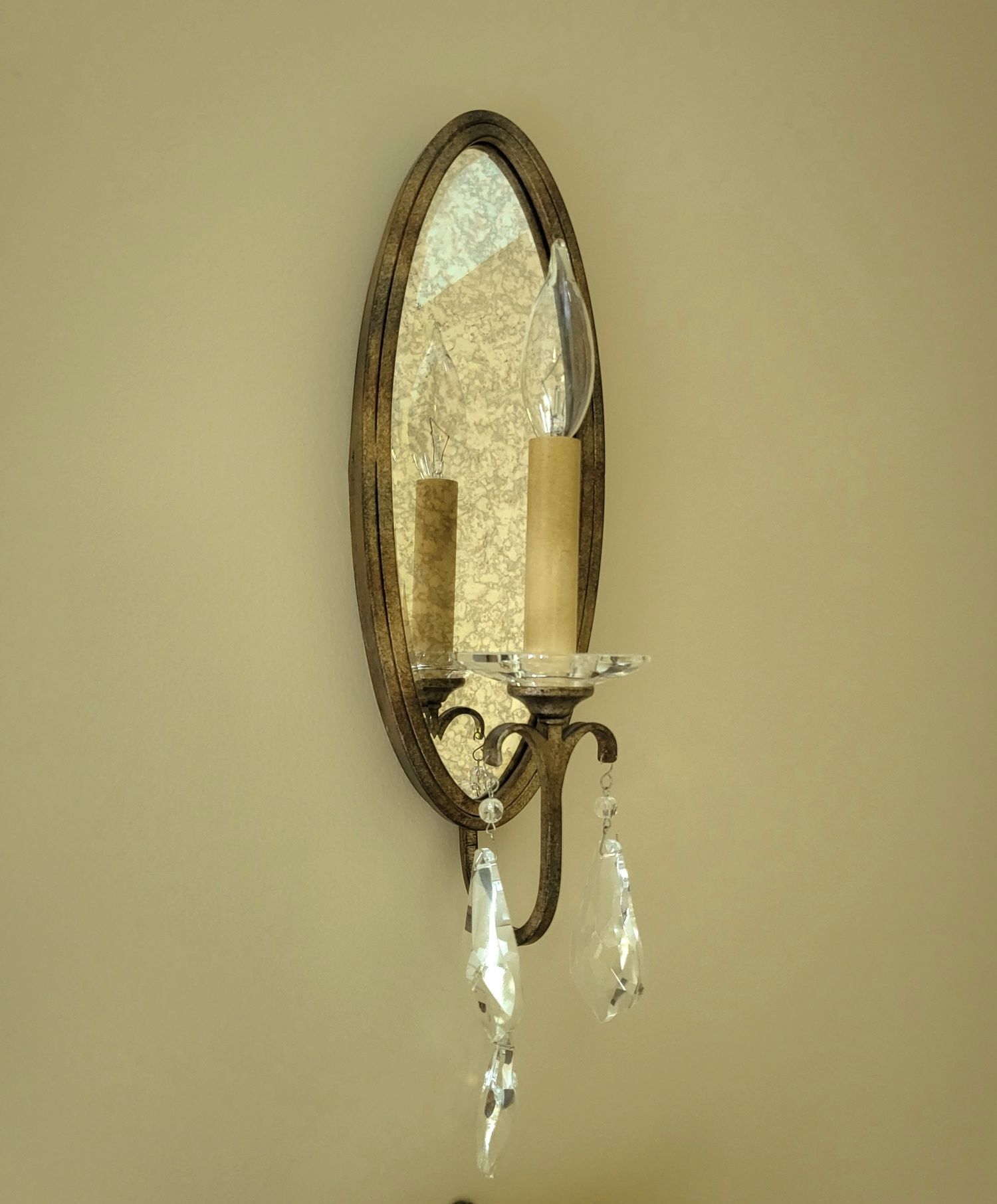 a wall light with a mirror and crystals on it