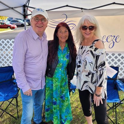 A man and two women are posing for a picture in front of a tent.