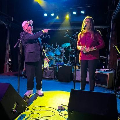 A man and a woman are singing into microphones on a stage.