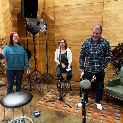 A group of people are standing around a microphone in a room.