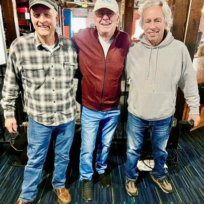 Three men are posing for a picture together in a room.