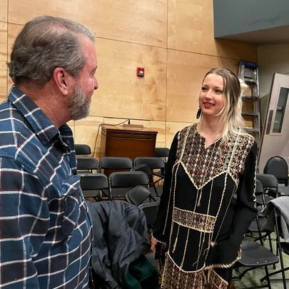 A man and a woman are standing next to each other in a room with chairs.