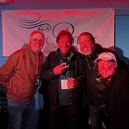 A group of men are posing for a picture in front of a sign that says peace