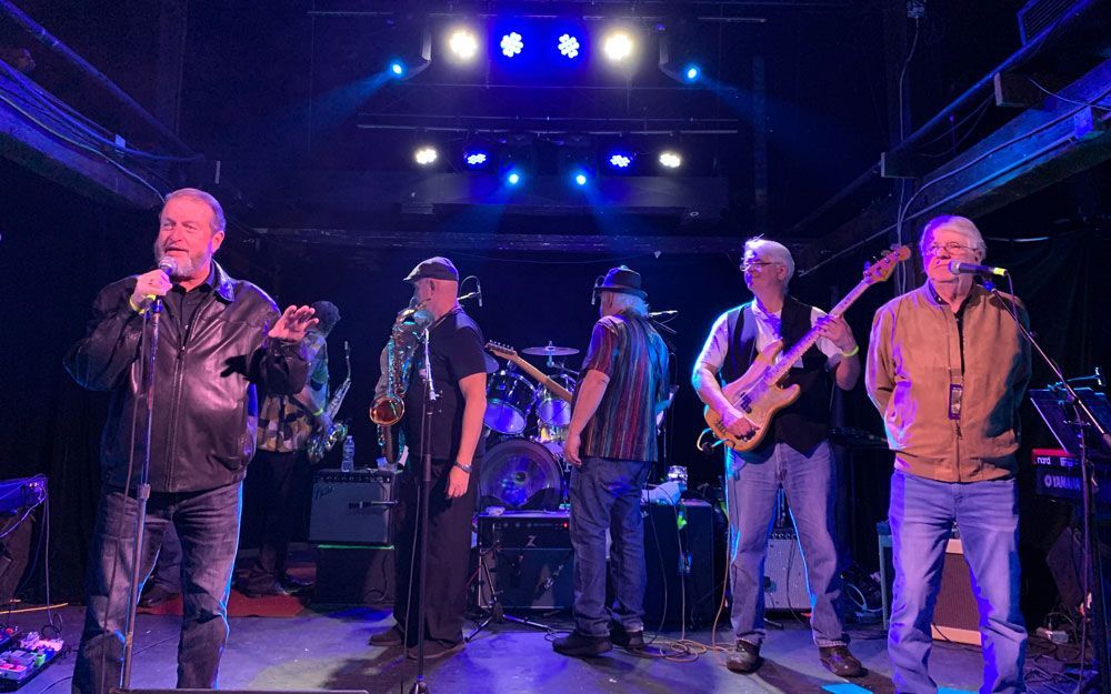 A group of men are standing on a stage playing instruments.