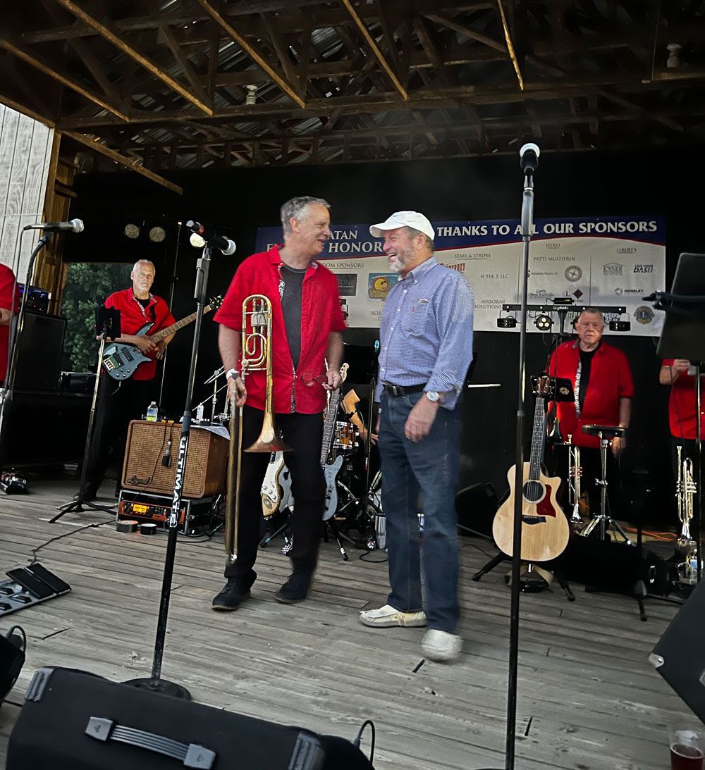 A man in a red jacket is playing a trombone in a band