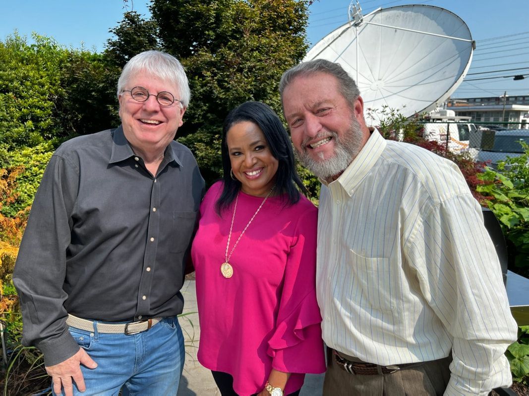Three people posing for a picture in front of a satellite dish