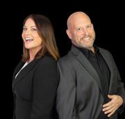 A man and a woman are standing back to back and smiling.
