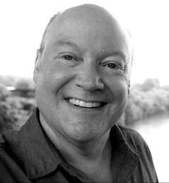 A man is smiling in a black and white photo.