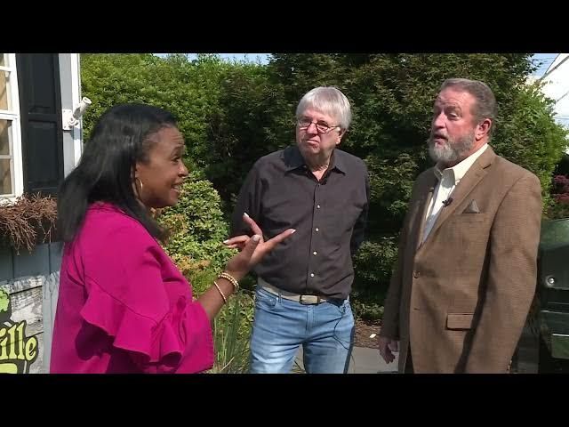 A woman in a pink shirt is talking to two men in suits.