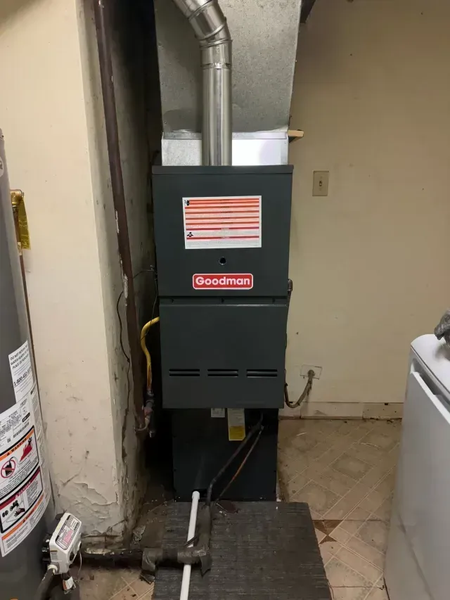 Goodman furnace in a utility room next to a water heater and washing machine.