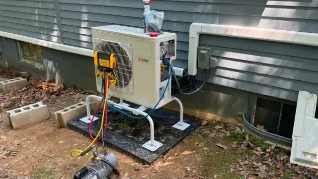 HVAC unit being serviced outdoors, with gauges and vacuum pump connected.
