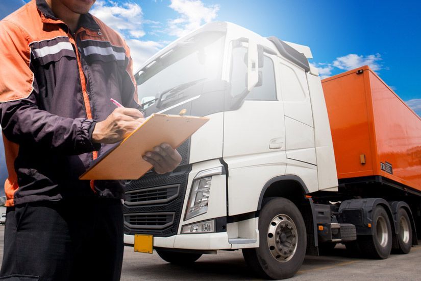 A Man Is Writing On A Clipboard In Front Of A Truck — KTM Towing In Crescent Head, NSW