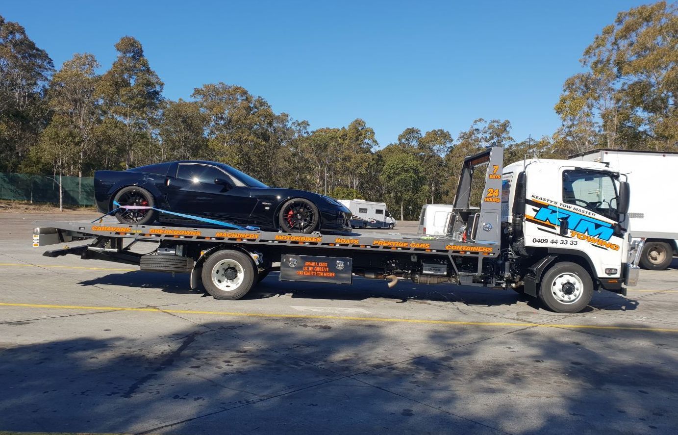 A Black Car Is Being Towed By A Tow Truck — KTM Towing In Kempsey, NSW