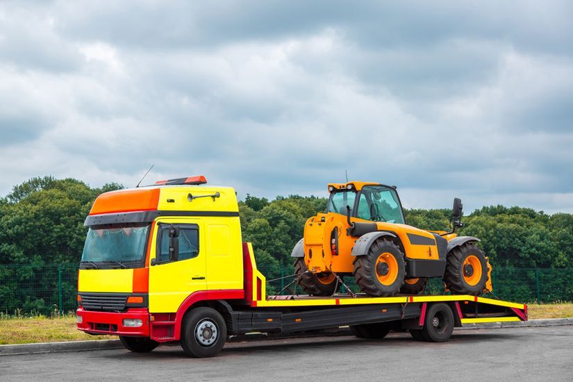 A Tow Truck Is Carrying A Tractor On The Back Of It — KTM Towing In Frederickton, NSW