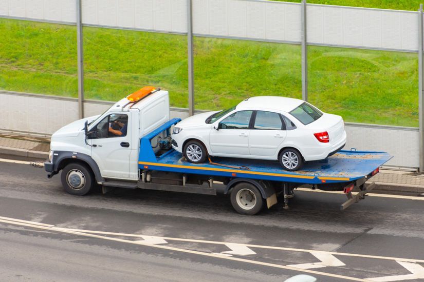 A Tow Truck Is Carrying A White Car On The Back Of It — KTM Towing In South West Rocks, NSW