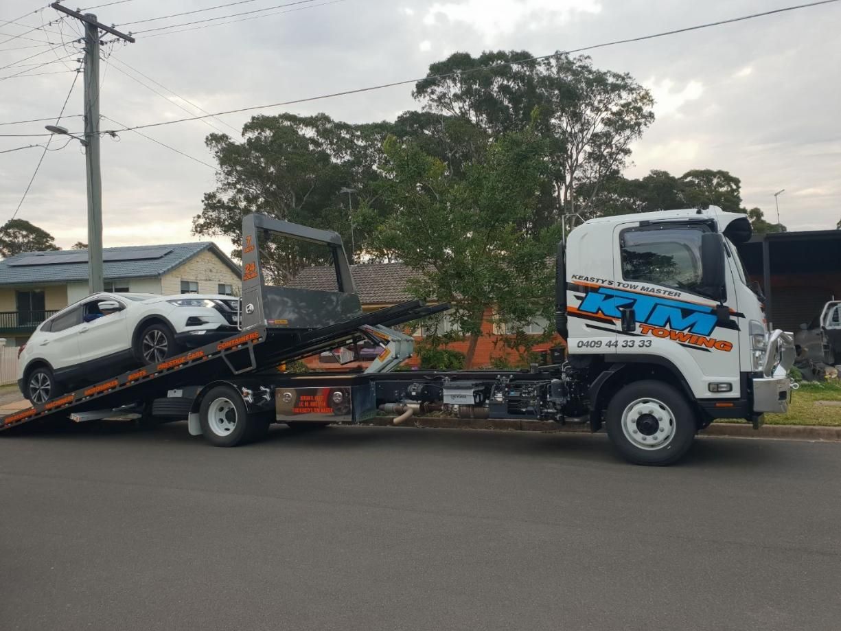 A White Car Is Being Towed By A Tow Truck — KTM Towing In Kempsey, NSW