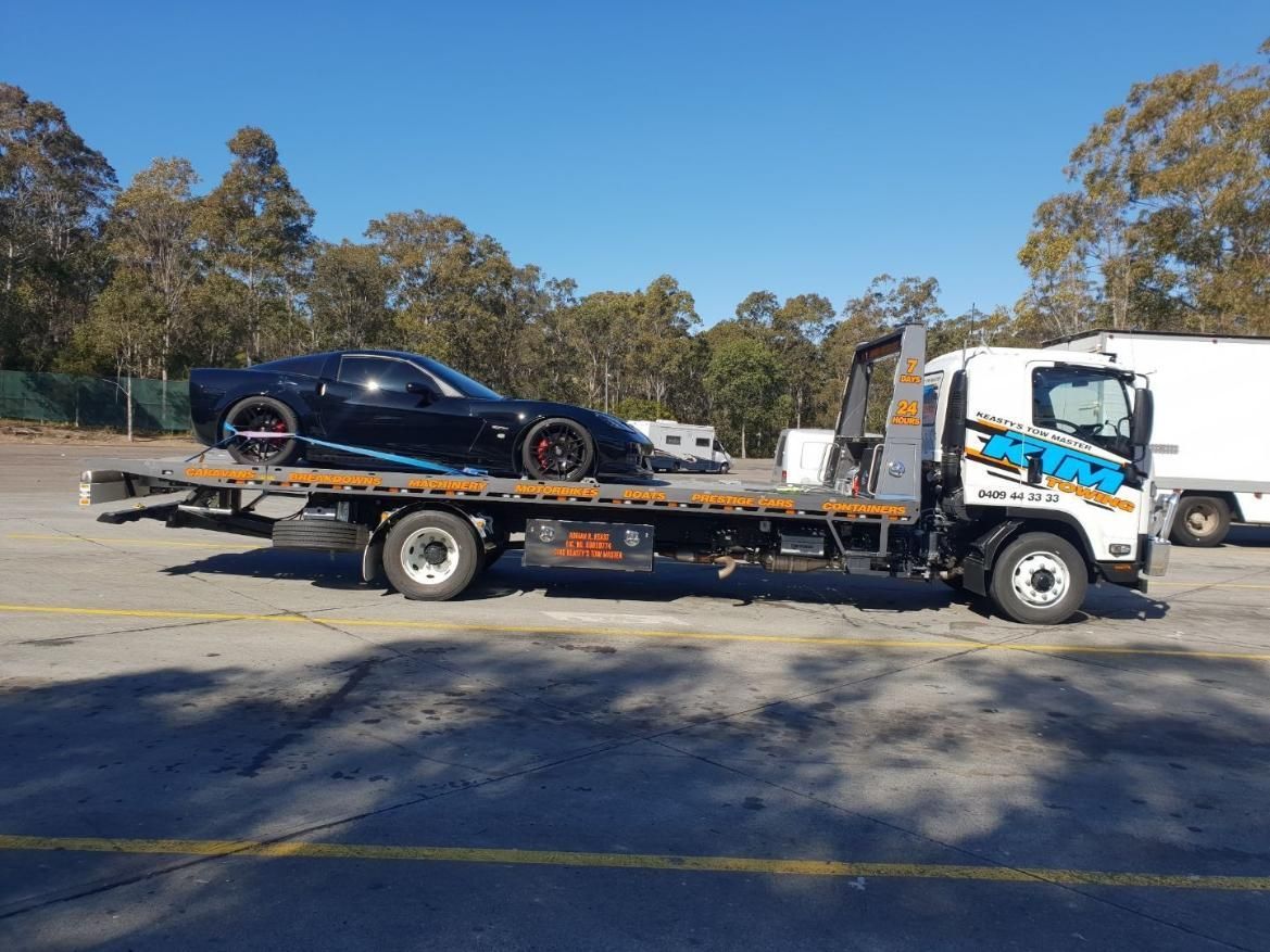 A Black Sports Car Is Being Towed By A Tow Truck — KTM Towing In Kempsey, NSW