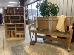 A wooden bench with a blanket on it is sitting in a room next to a bookshelf.